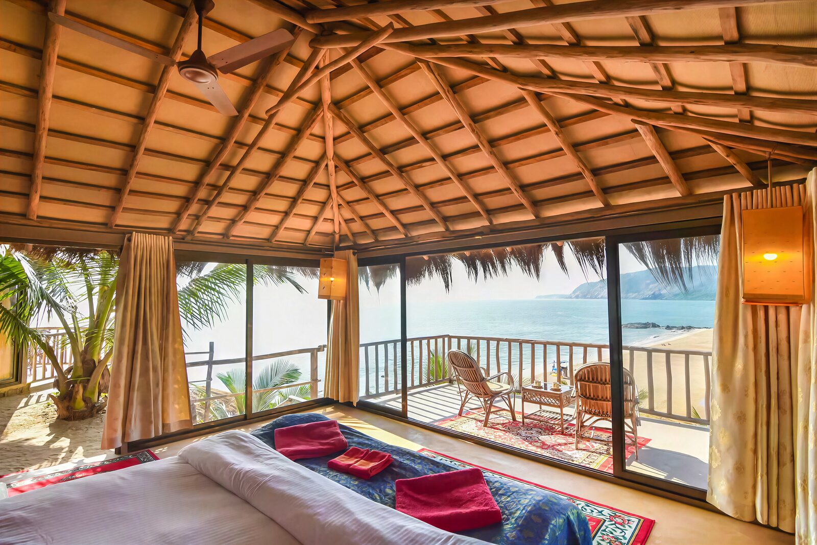 A bed facing a wall of glass, the balcony and the sea beyond in morning light